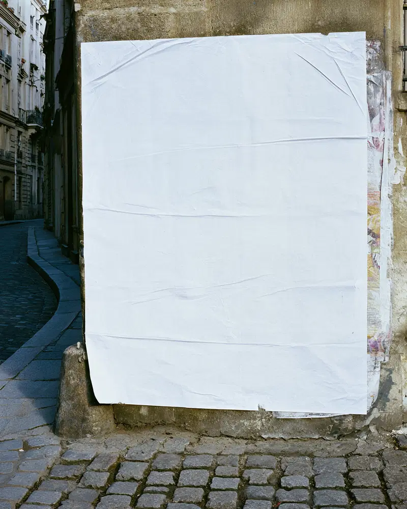 Blank white poster on old urban wall with cobblestone street