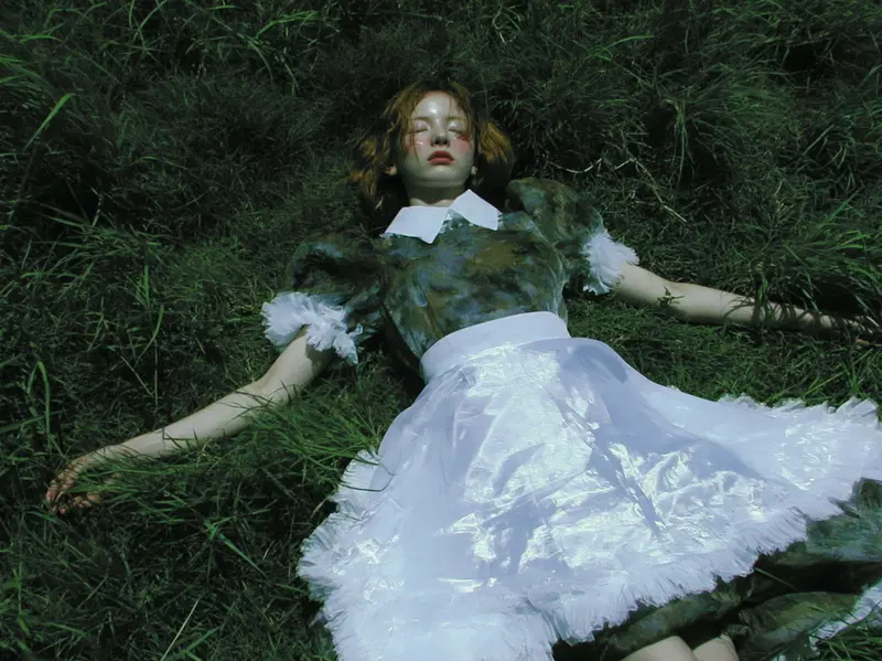 Artistic portrait of a woman lying on grass with vintage-inspired clothing