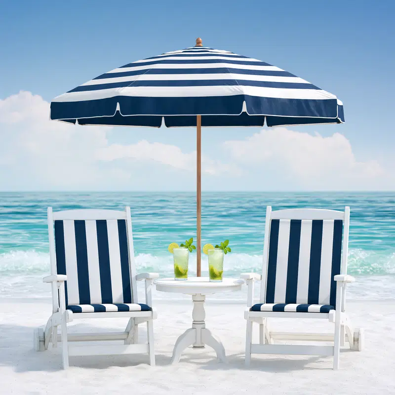Beach scene with striped chairs, umbrella, and refreshing drinks by the sea
