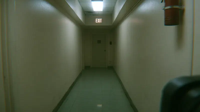 Dimly Lit Narrow Corridor with Exit Sign and Closed Door