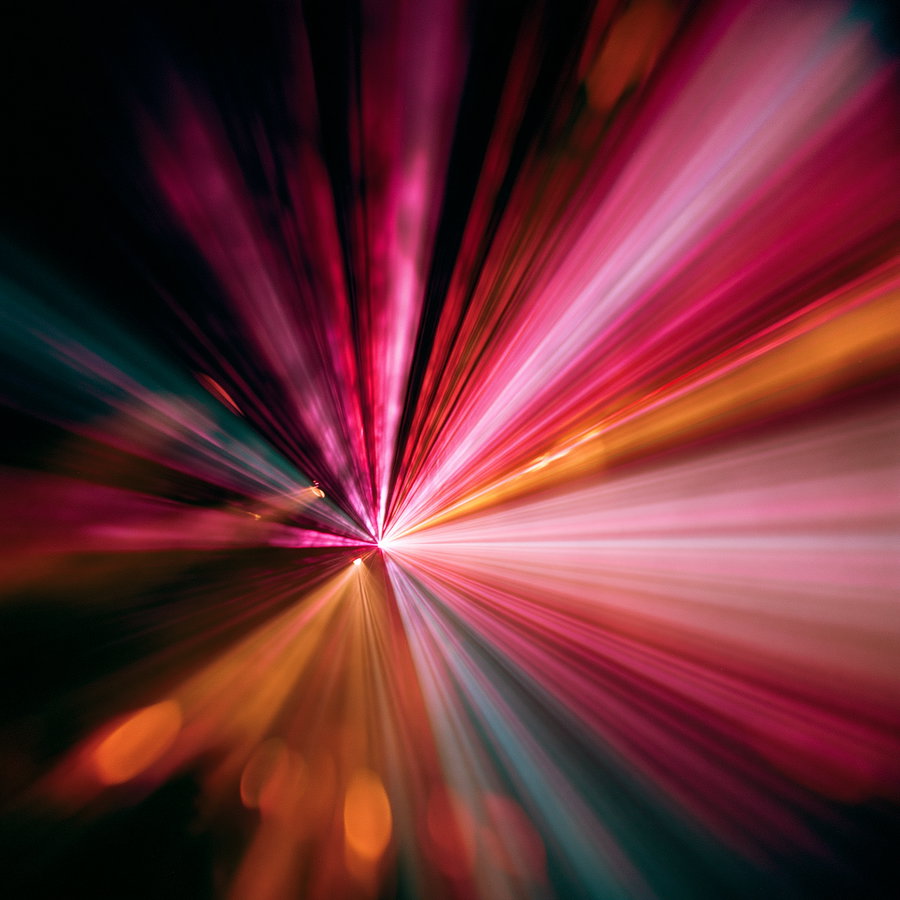 Abstract image featuring a radial burst of vibrant colors including pink, orange, and teal, with a dynamic light streak effect radiating from the center.