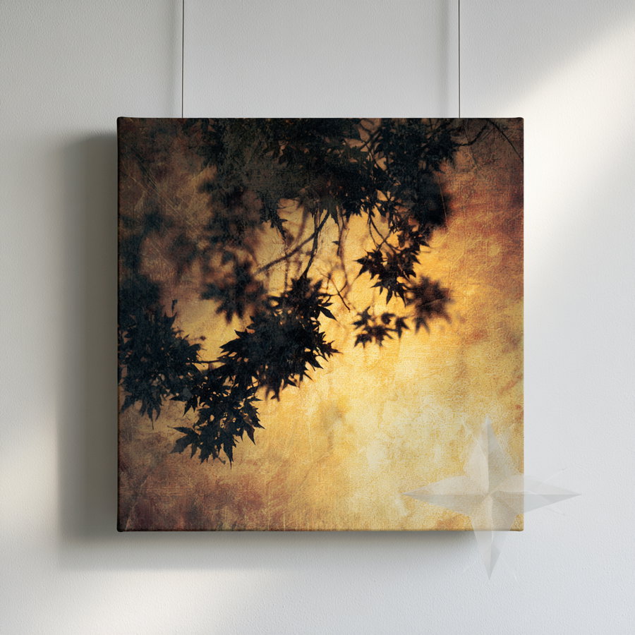 Canvas wall art showing dark tree branches with leaves silhouetted against a golden and brown textured backdrop