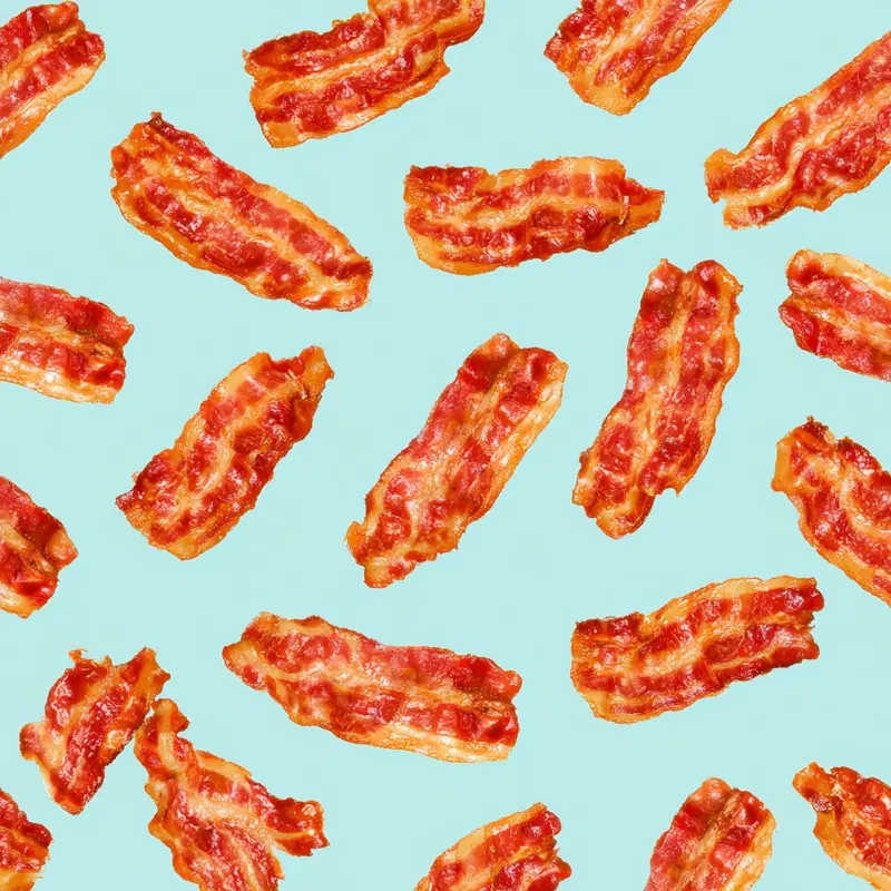 Pattern of crispy bacon strips on a light blue background