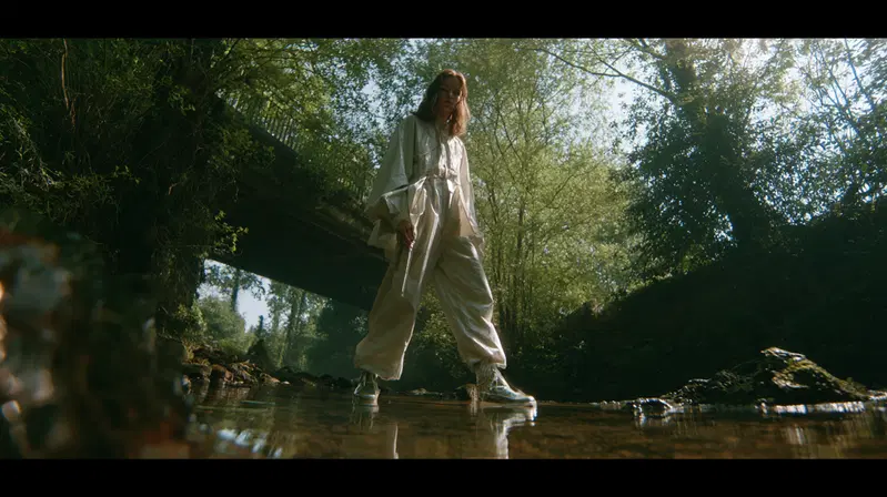 Artistic portrait of a person standing in a shallow stream under a bridge