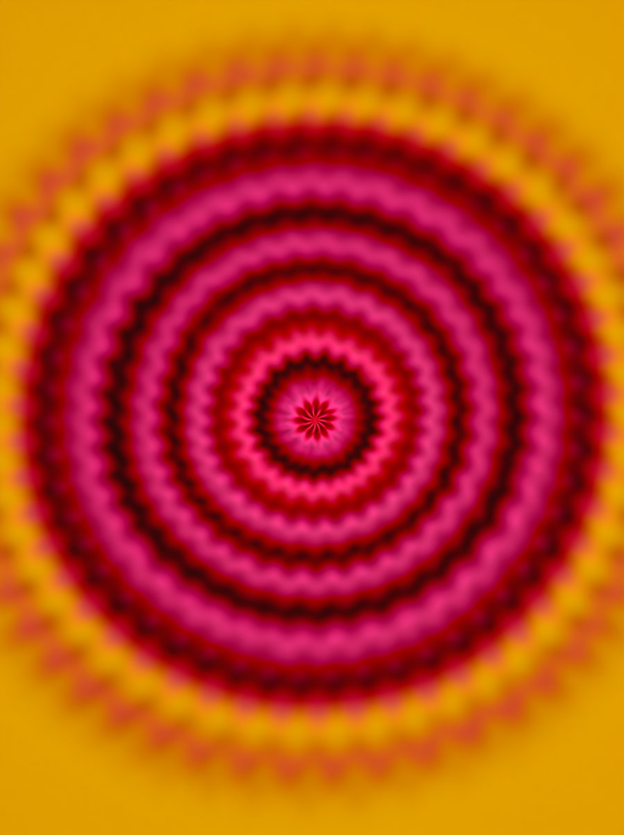 Concentric ring pattern with vibrant pink, red, and yellow colors radiating from the center, creating a hypnotic visual effect