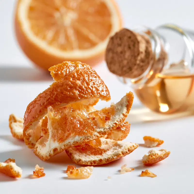 Close-up of peeled tangerine and a small glass bottle with cork