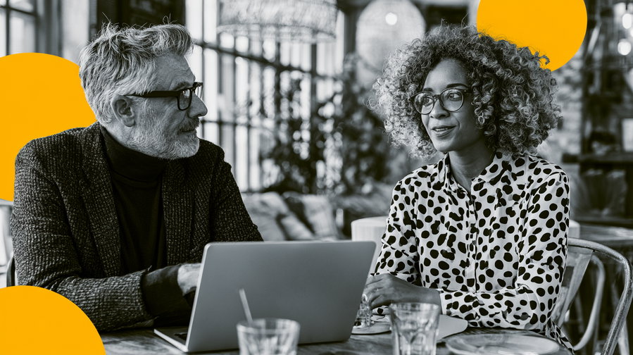 A grayscale photo showing a man and a woman talking at a table with a laptop, decorated with abstract yellow shapes in the background.