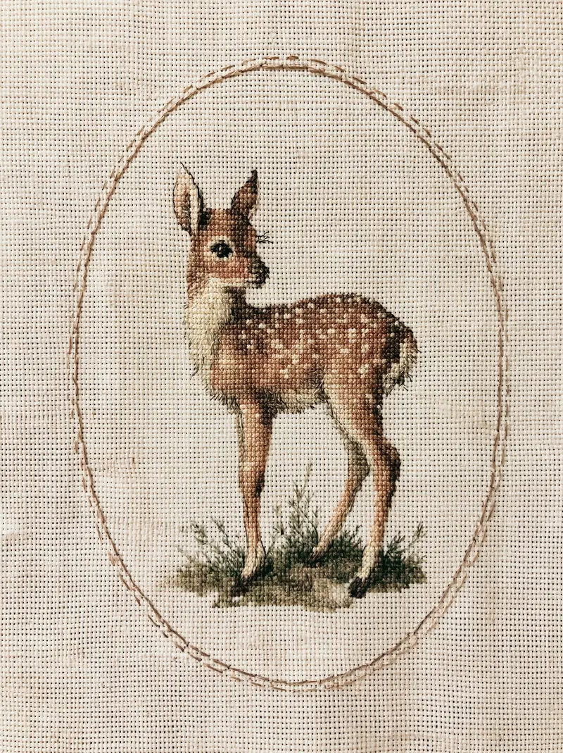 Detailed Embroidery of a Young Deer Surrounded by Greenery on Fabric