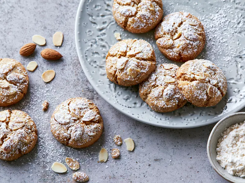 Close-up of almond cookies dusted with powdered sugar on a decorative plate
