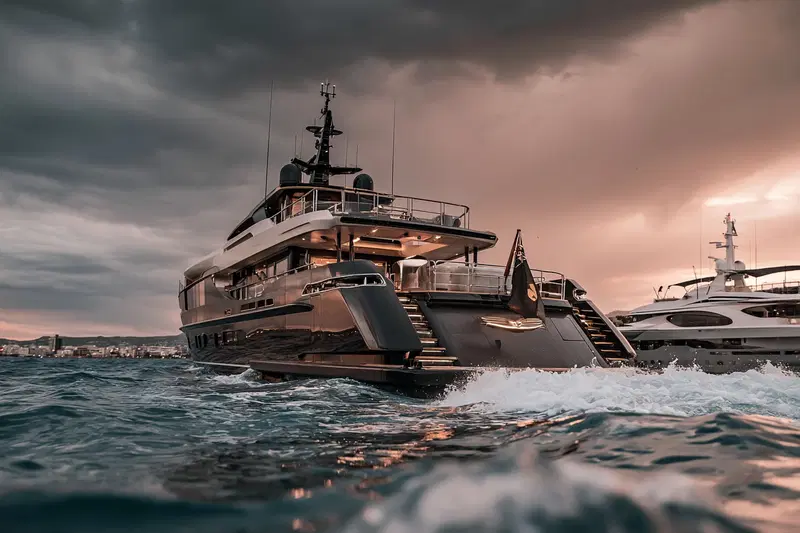 Luxury yachts navigating calm waters under dramatic cloudy skies