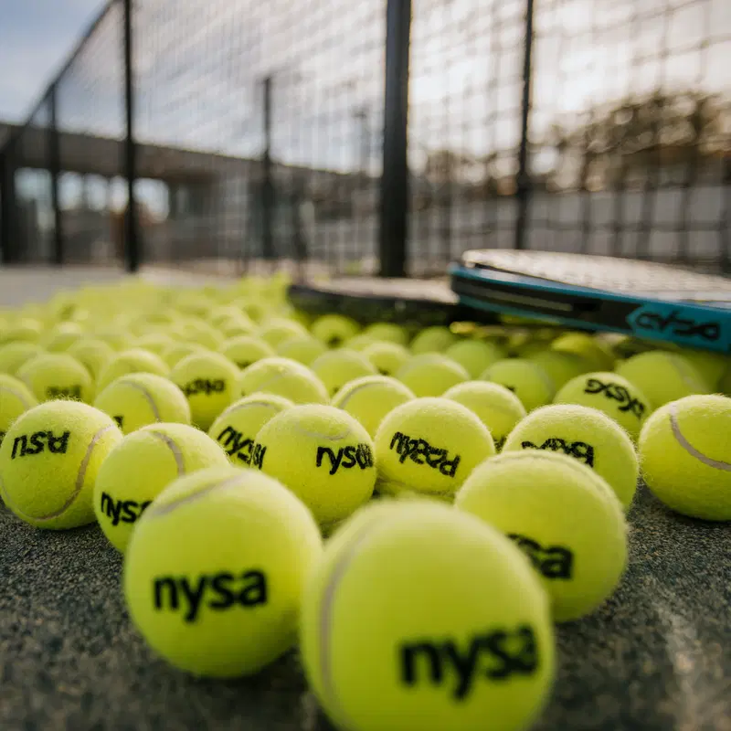 Close-up of tennis balls and a racket on a tennis court