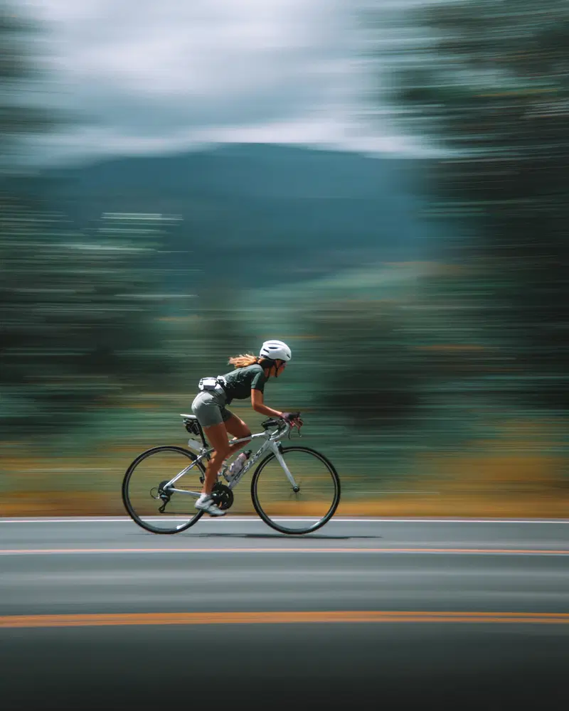 Cyclist riding fast on a road with a blurred nature background