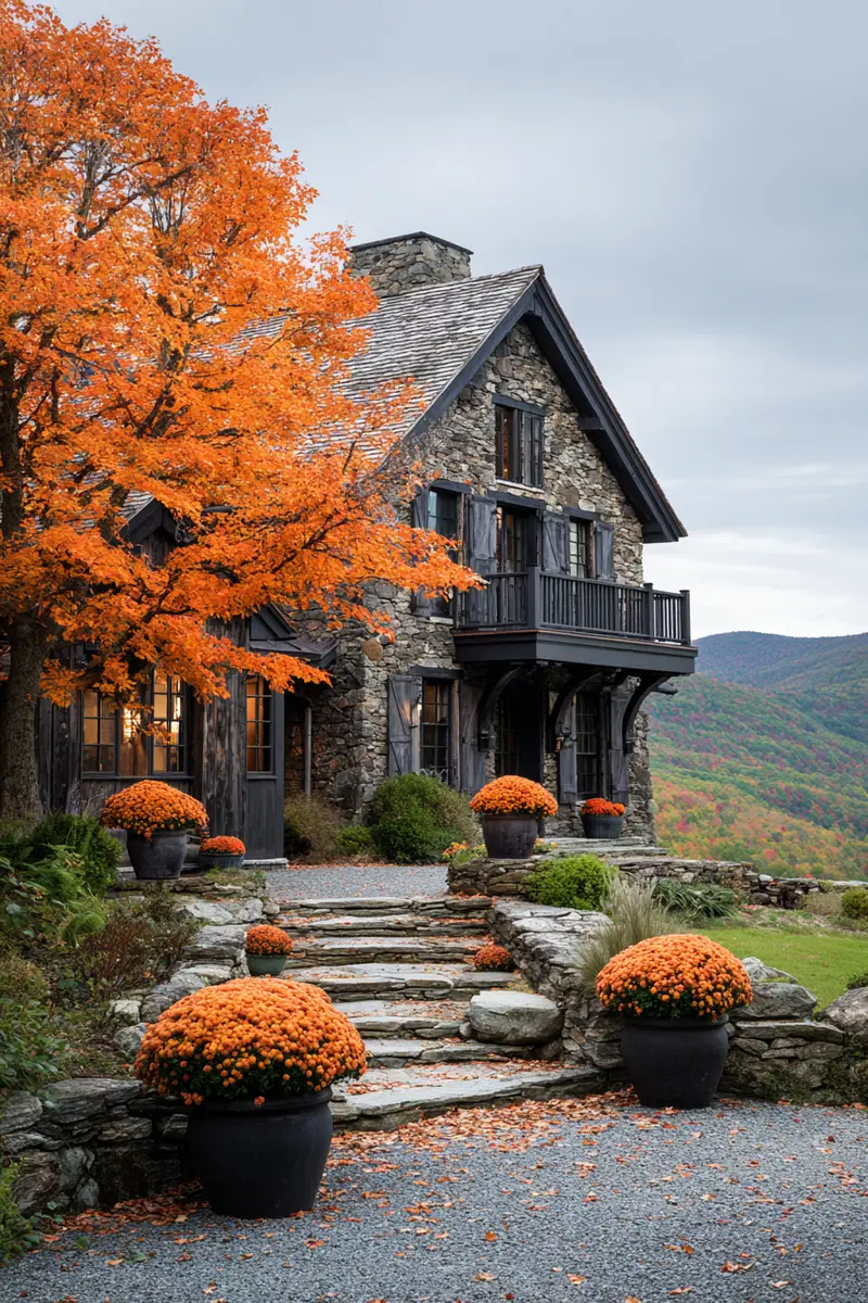 Rustic stone house with vibrant orange autumn foliage and flower pots