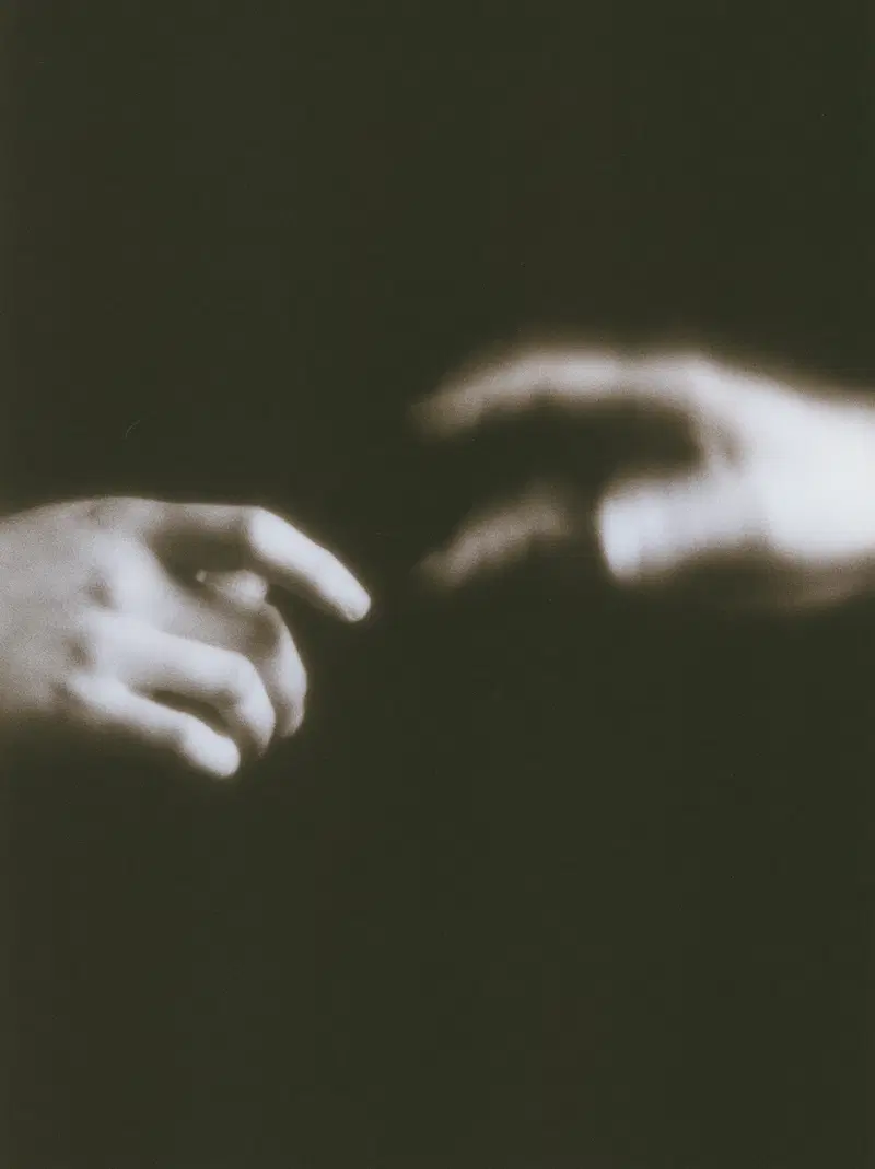 Black and white artistic photo of two hands reaching towards each other