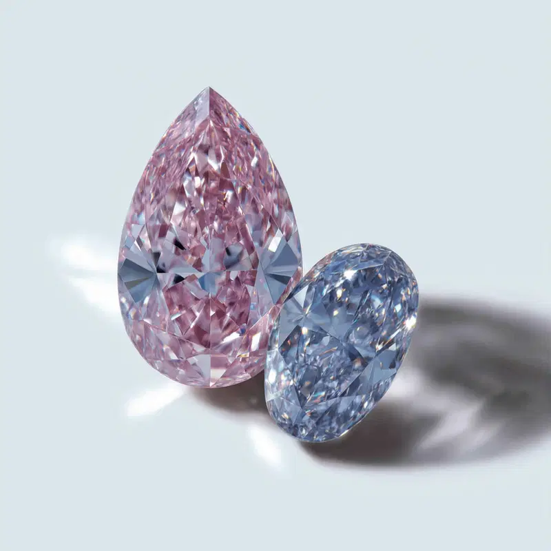 Close-up of two intricately faceted gemstones against a light background