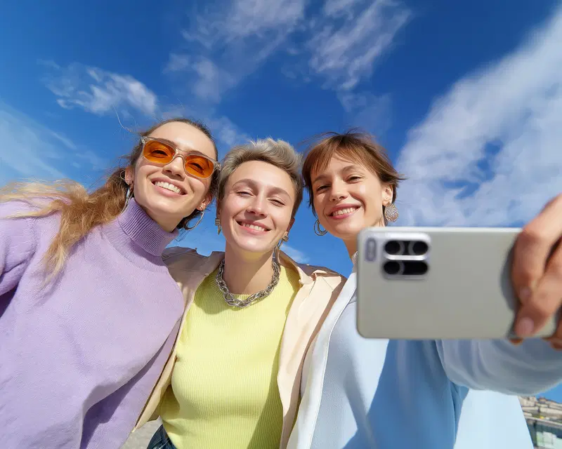 Happy young women taking a cheerful selfie outdoors under clear blue sky