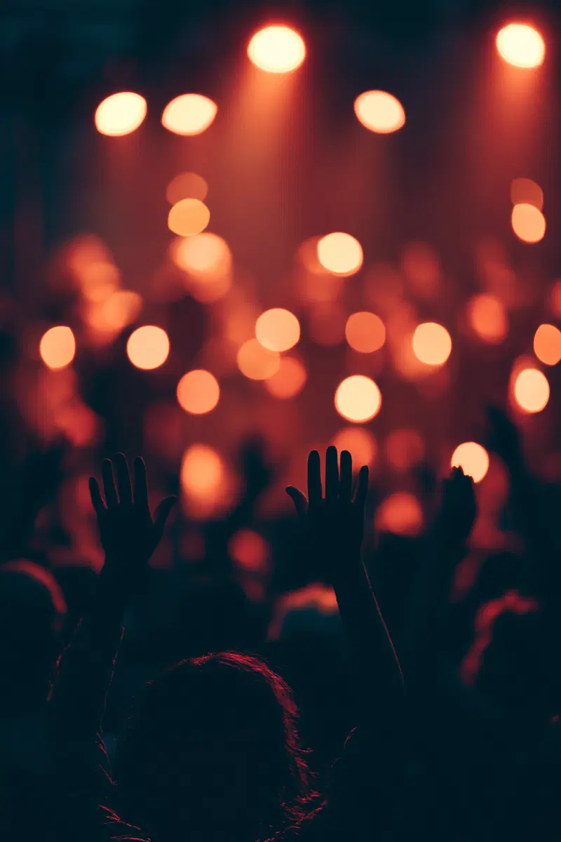 Moody Atmosphere at a Live Music Event with Raised Hands and Warm Lighting