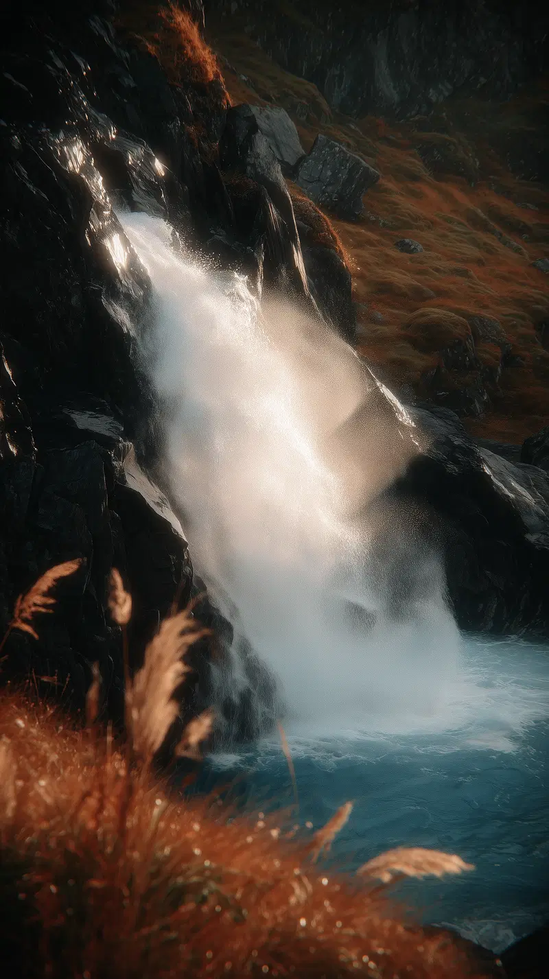 Scenic waterfall cascading over dark rocks into a blue pool with autumn grass