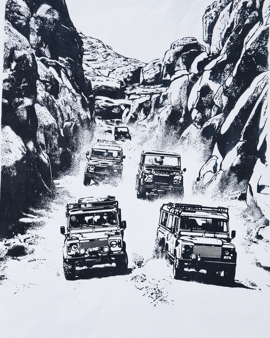 Black and white drawing depicting five off-road vehicles driving rugged paths between high rocky cliffs, kicking up dust