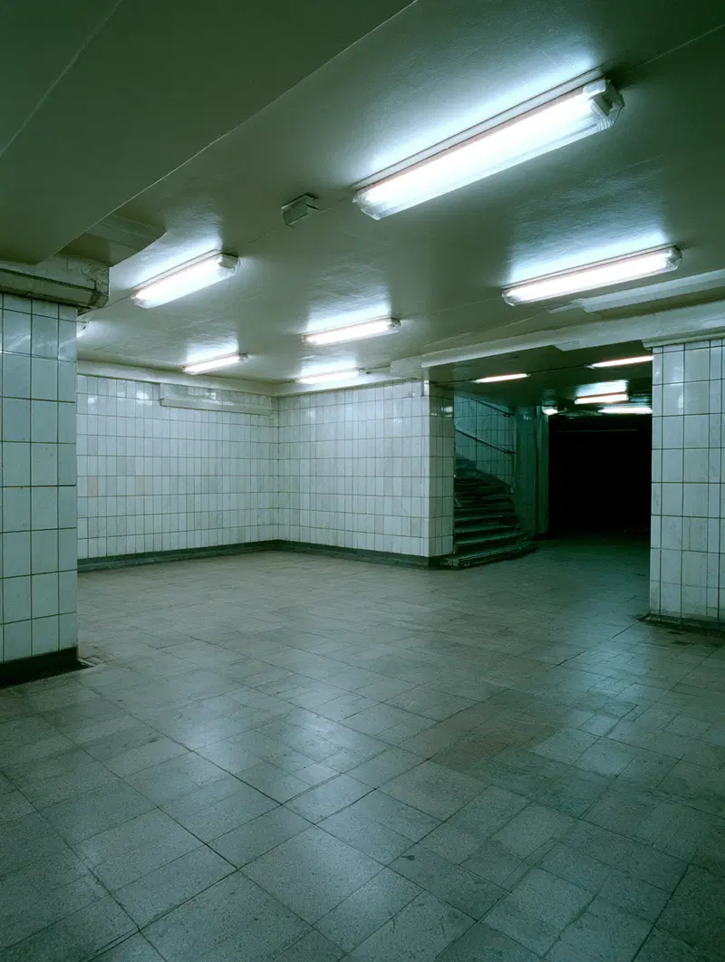 Moody underground corridor with tiled walls and fluorescent lighting