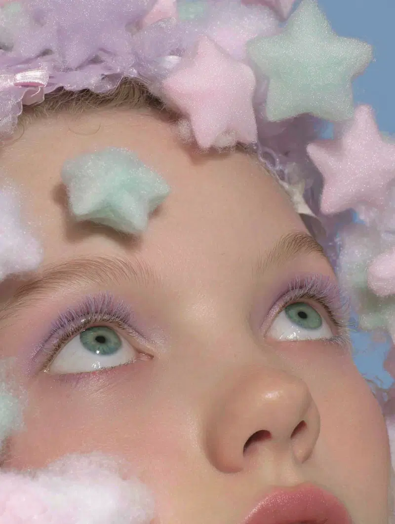 Close-up portrait of a person with pastel star-shaped decorations and soft purple makeup