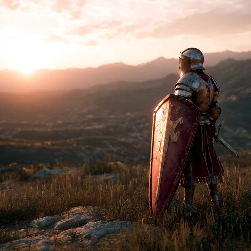 Medieval knight standing on a rocky hill overlooking a sunset landscape