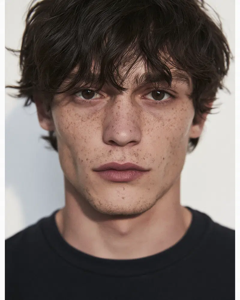 Close-up portrait of a young man with freckles and tousled dark hair