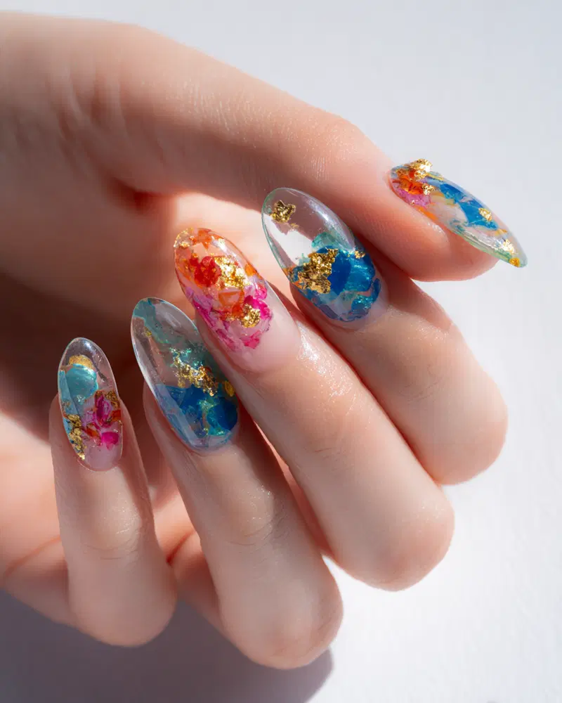 Close-up of colorful artistic nail art design with gold leaf accents