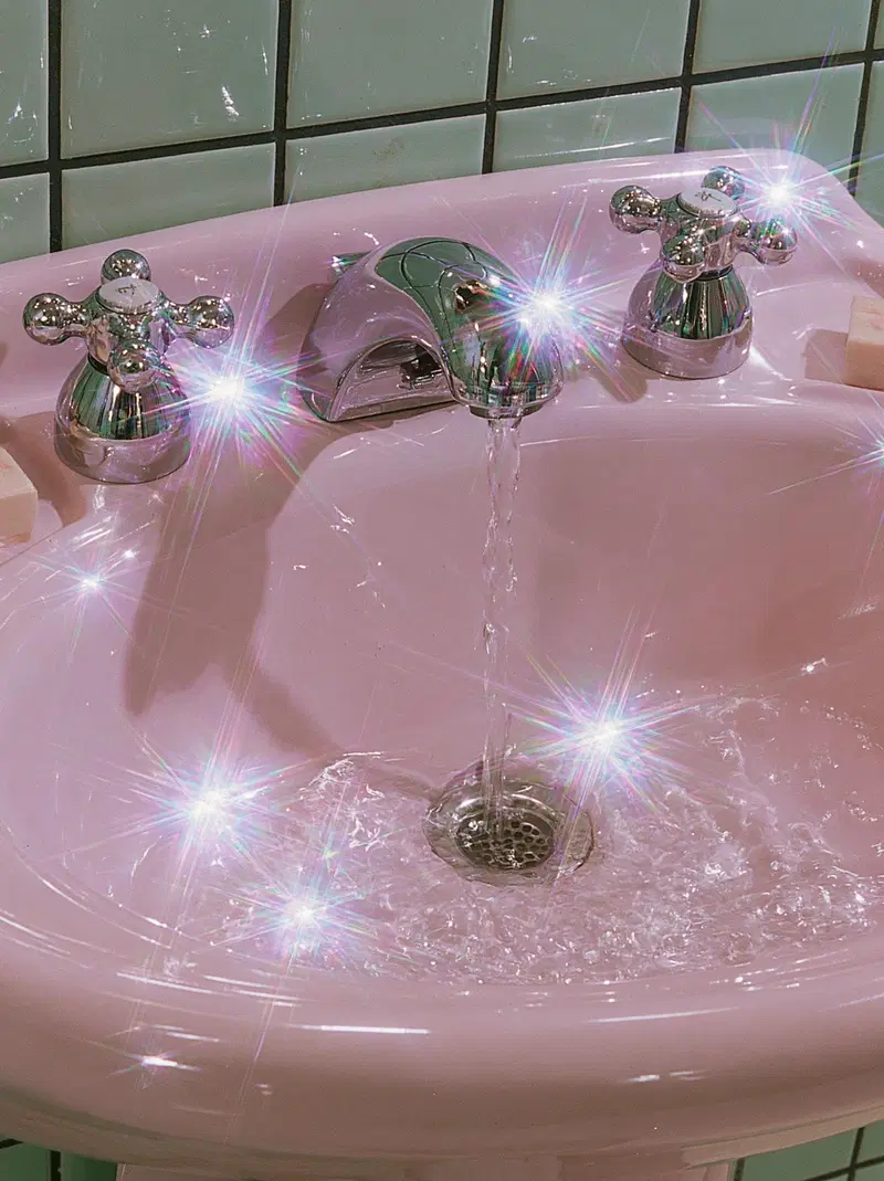 Pink vintage bathroom sink with chrome faucets and sparkling water flow