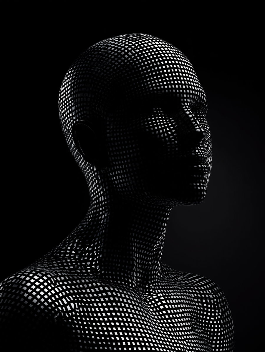 A black and white abstract image of a human figure covered in a grid pattern of light and dark squares on a dark background