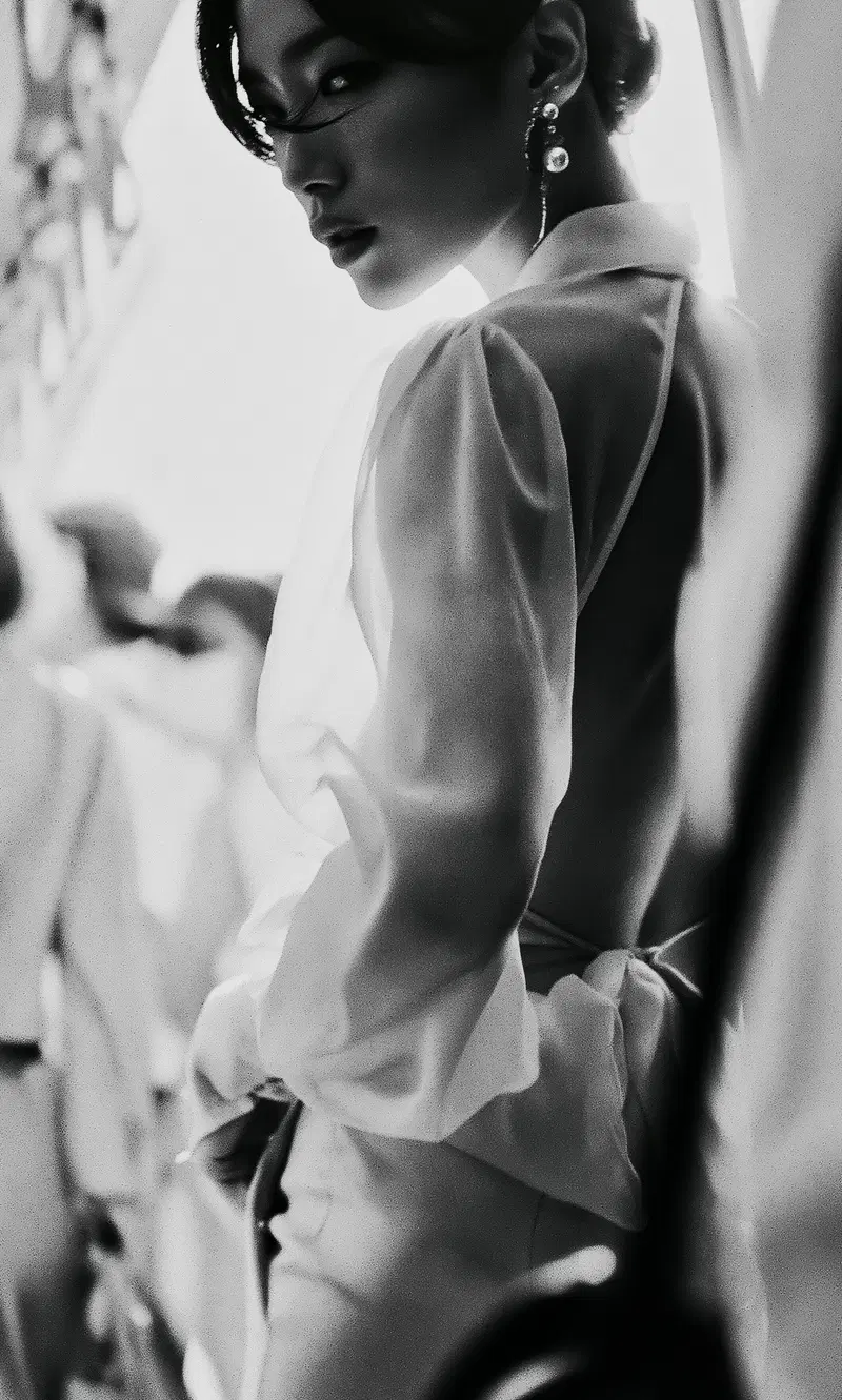 Elegant black and white portrait of a woman in sheer clothing and statement earrings