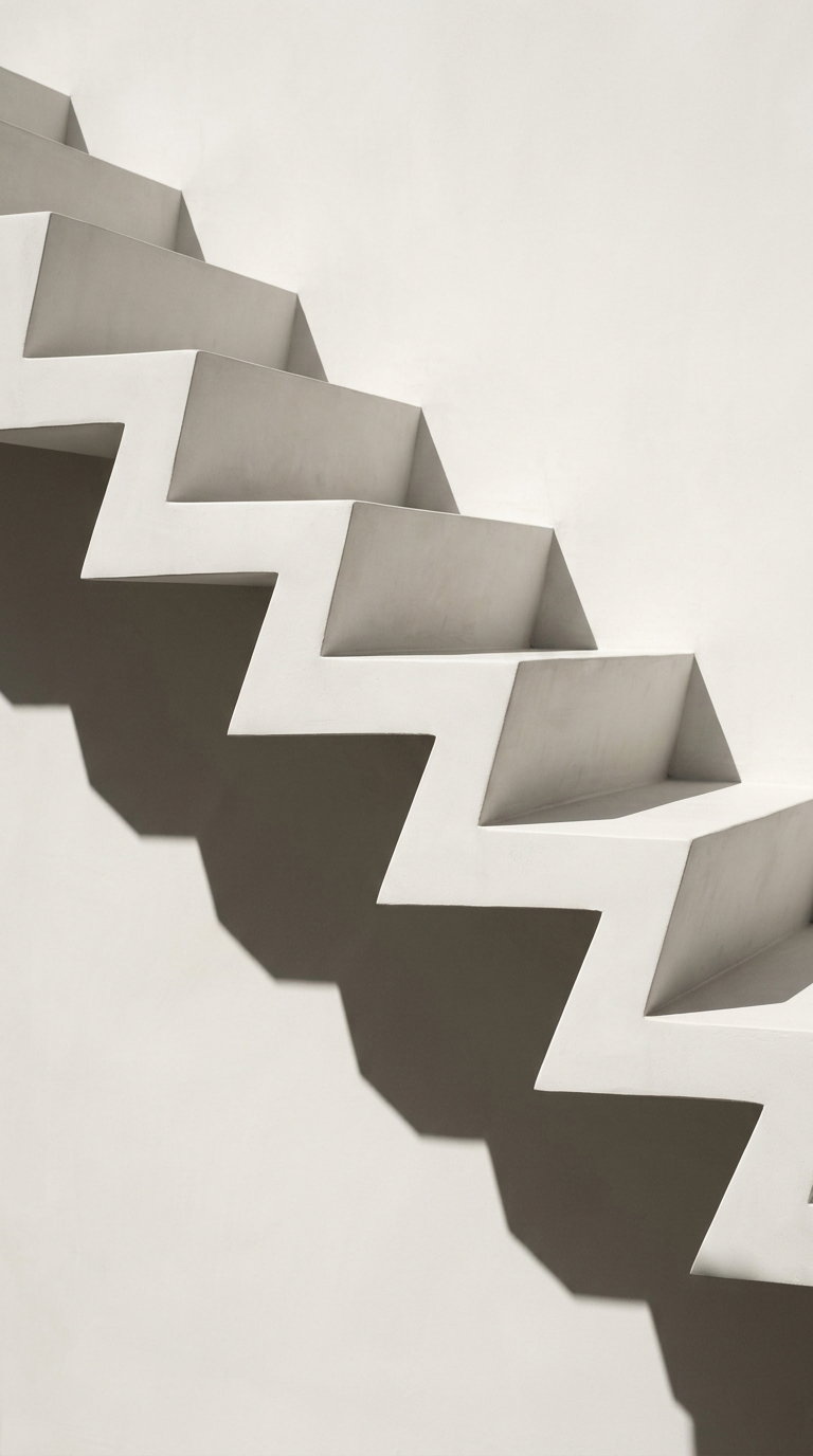 White stair steps with sharp angles casting dark, zigzag shadows on a plain light-colored wall
