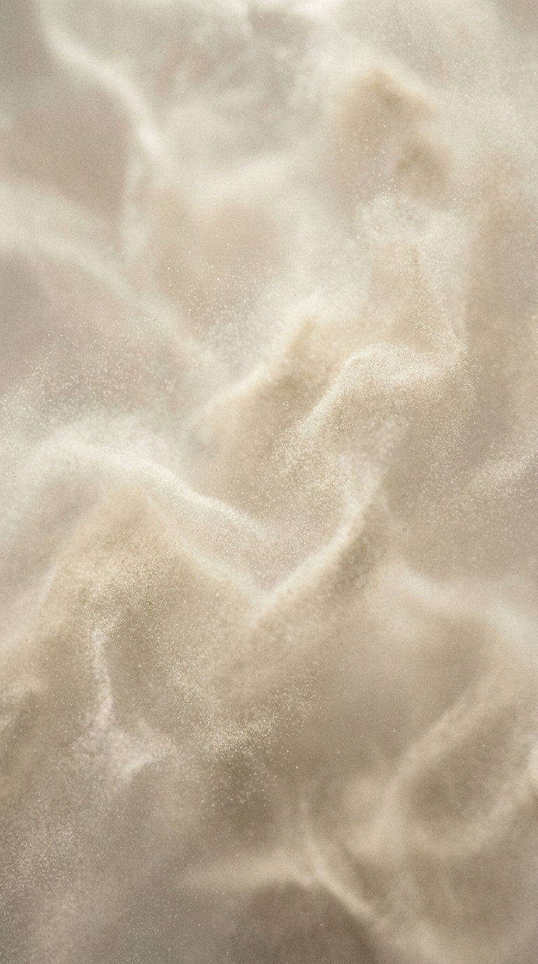 Close-up image of delicate, soft beige and cream textures resembling gentle swirling clouds or fabric folds
