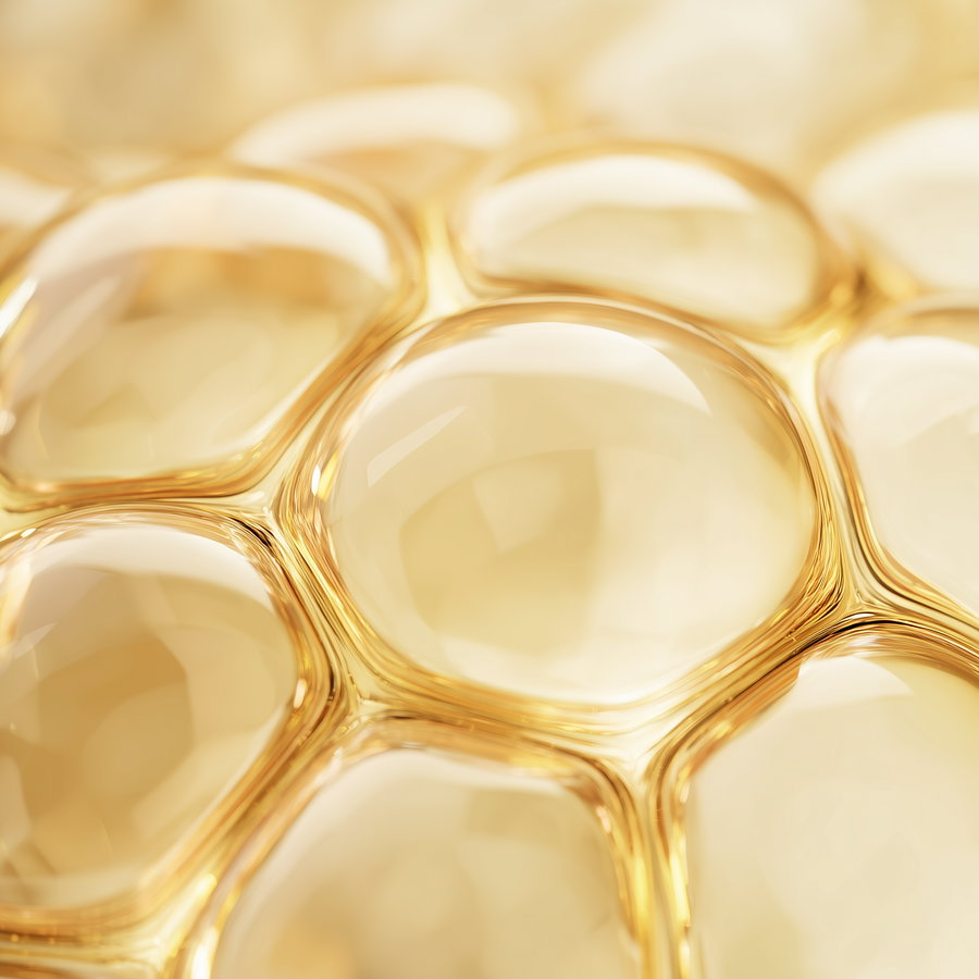 Macro shot of several smooth golden transparent bubbles clustered together with highlights and reflections