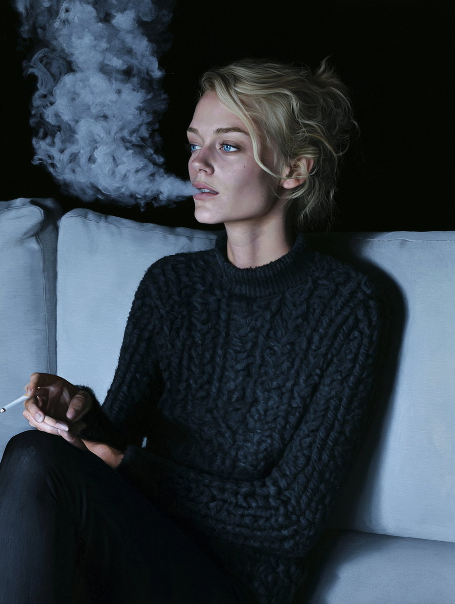 A blonde woman with blue eyes wearing a chunky dark knitted sweater sits on a light-colored couch, holding a cigarette in one hand and exhaling a thick smoke plume against a black background.