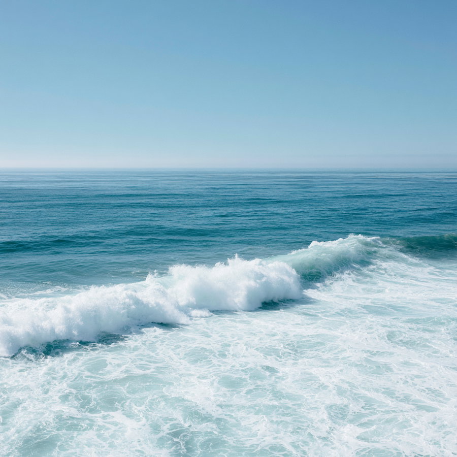View of the ocean with waves crashing and a clear blue sky above