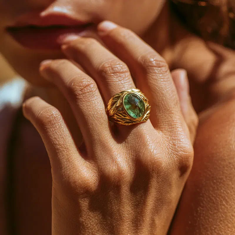 Stylized Leaf Ring with Green Gemstone on Sunlit Skin