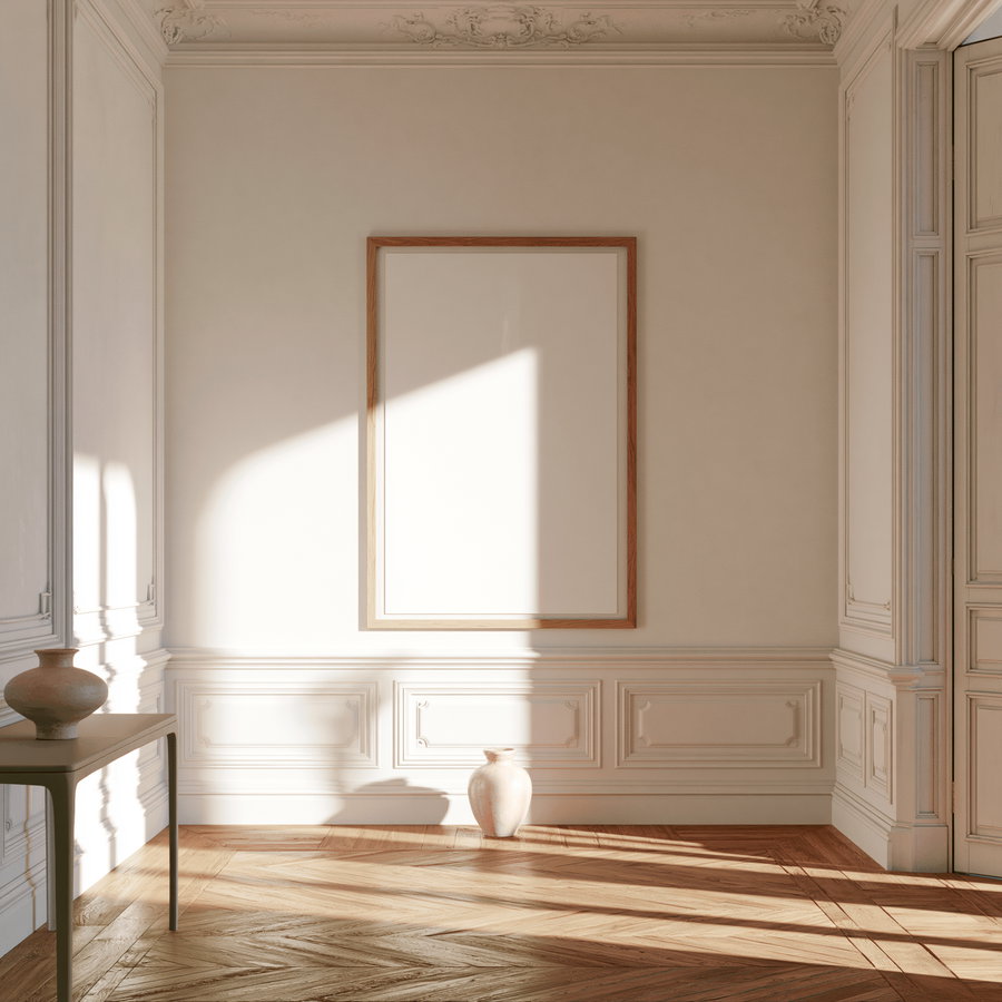 A bright and airy hallway featuring a large natural oak picture frame hanging on a plain panelled wall. The frame holds a blank white poster, with a slim console table and a pale ceramic vase in the foreground. Soft daylight illuminates the space, highlighting the warm oak floor and classic wainscoting panel moulding.