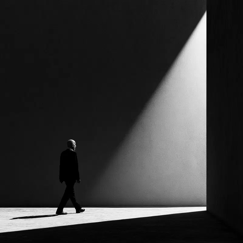 High Contrast Black and White Photo of a Man Walking in Light