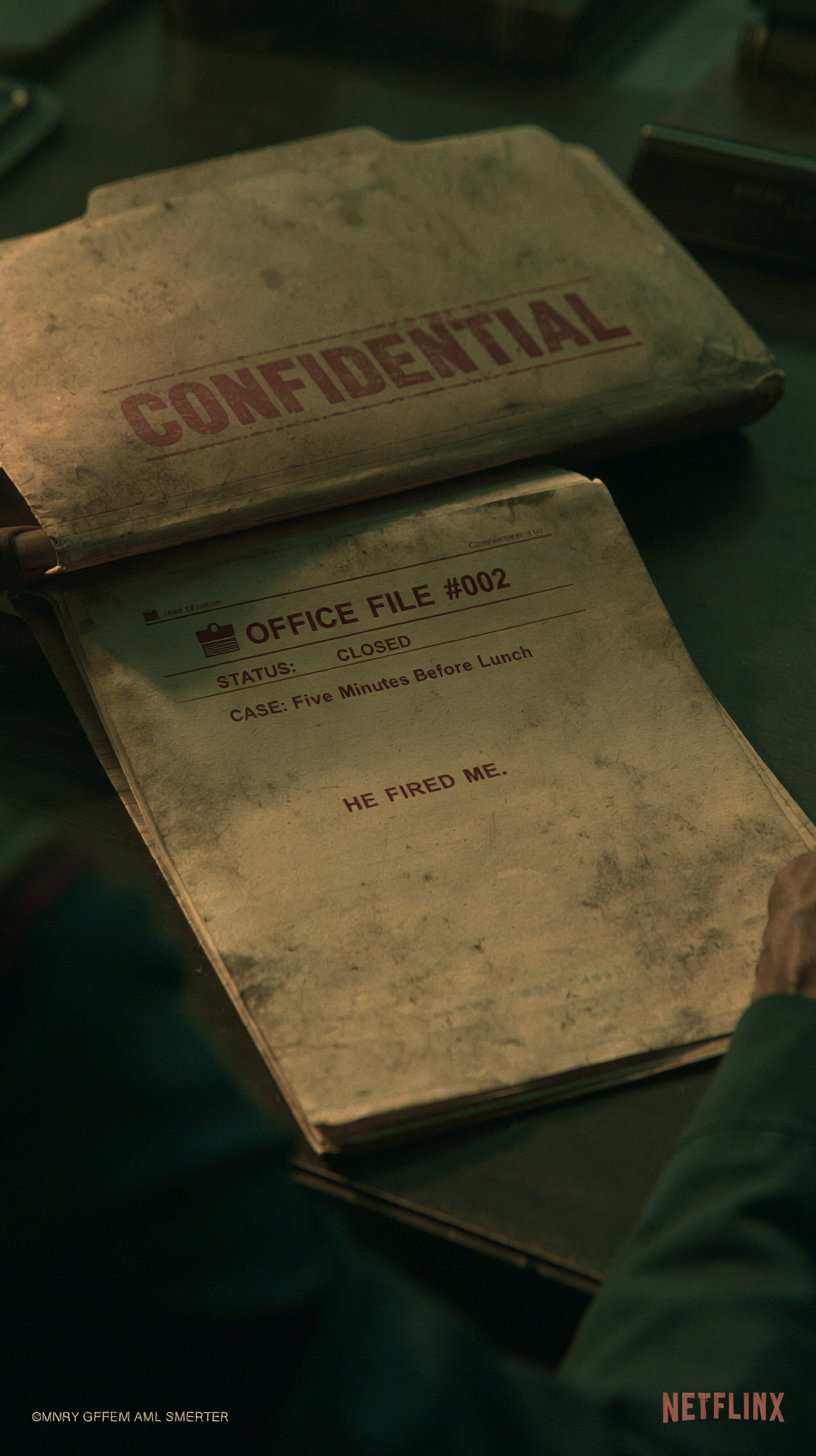 A worn manila folder with a red 'CONFIDENTIAL' stamp on a dark desk, partially open, revealing a page that reads 'OFFICE FILE #002 STATUS: CLOSED CASE: Five Minutes Before Lunch' followed by 'HE FIRED ME.'