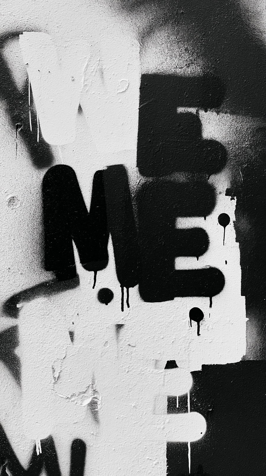 Black and white graffiti on a wall displaying the words 'We and Me' in bold letters.