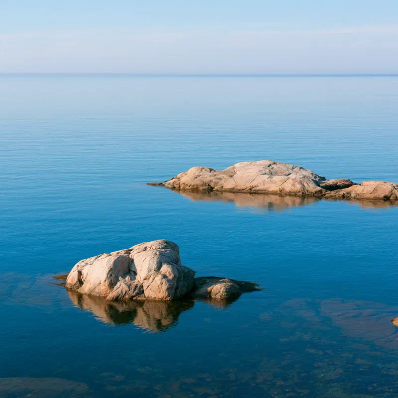 Serene Summer Morning Over Blue Ocean with Light Rocks
