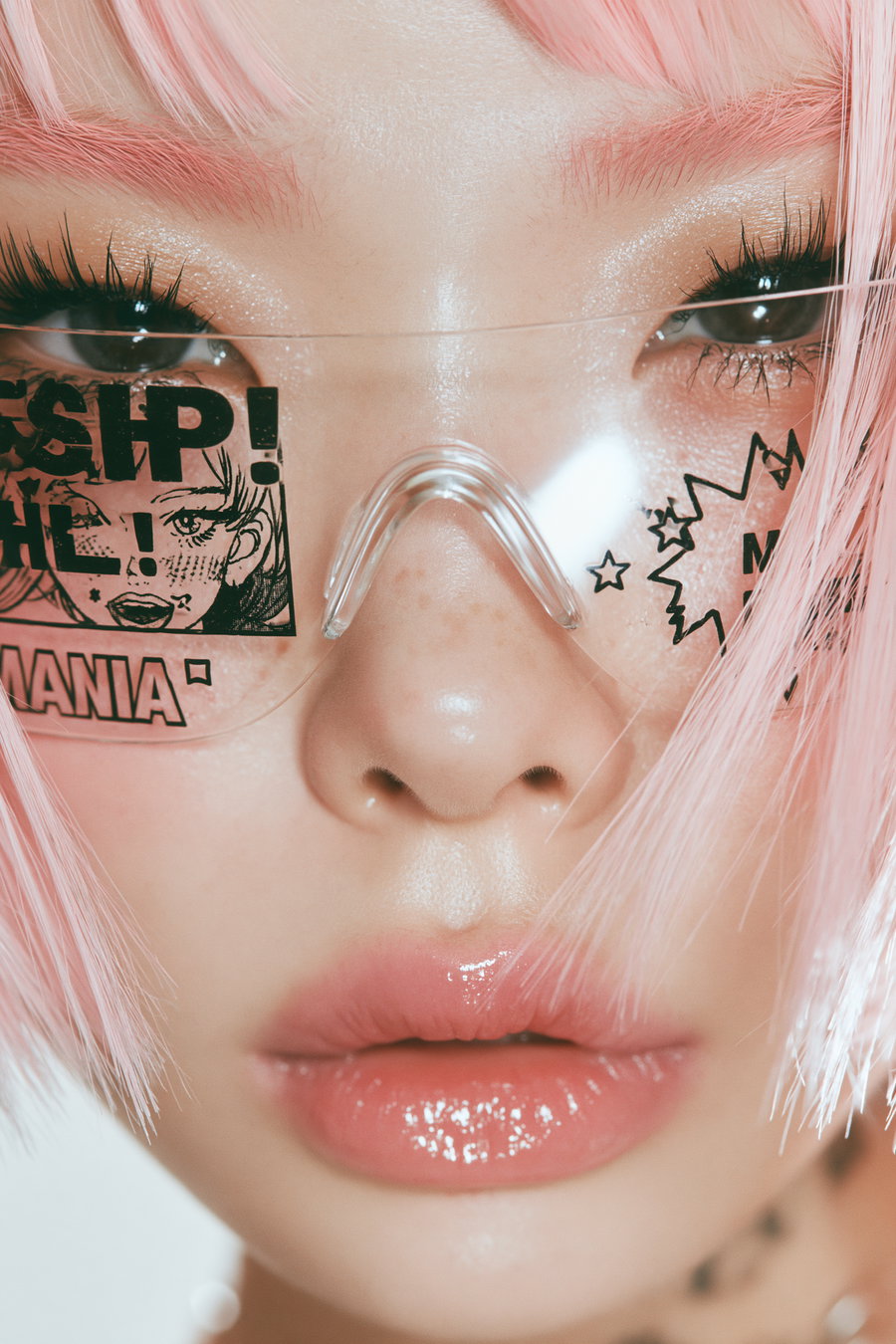 Close-up portrait of a person with pink hair and manga-themed glasses, showcasing a glossy expression and detailed makeup.