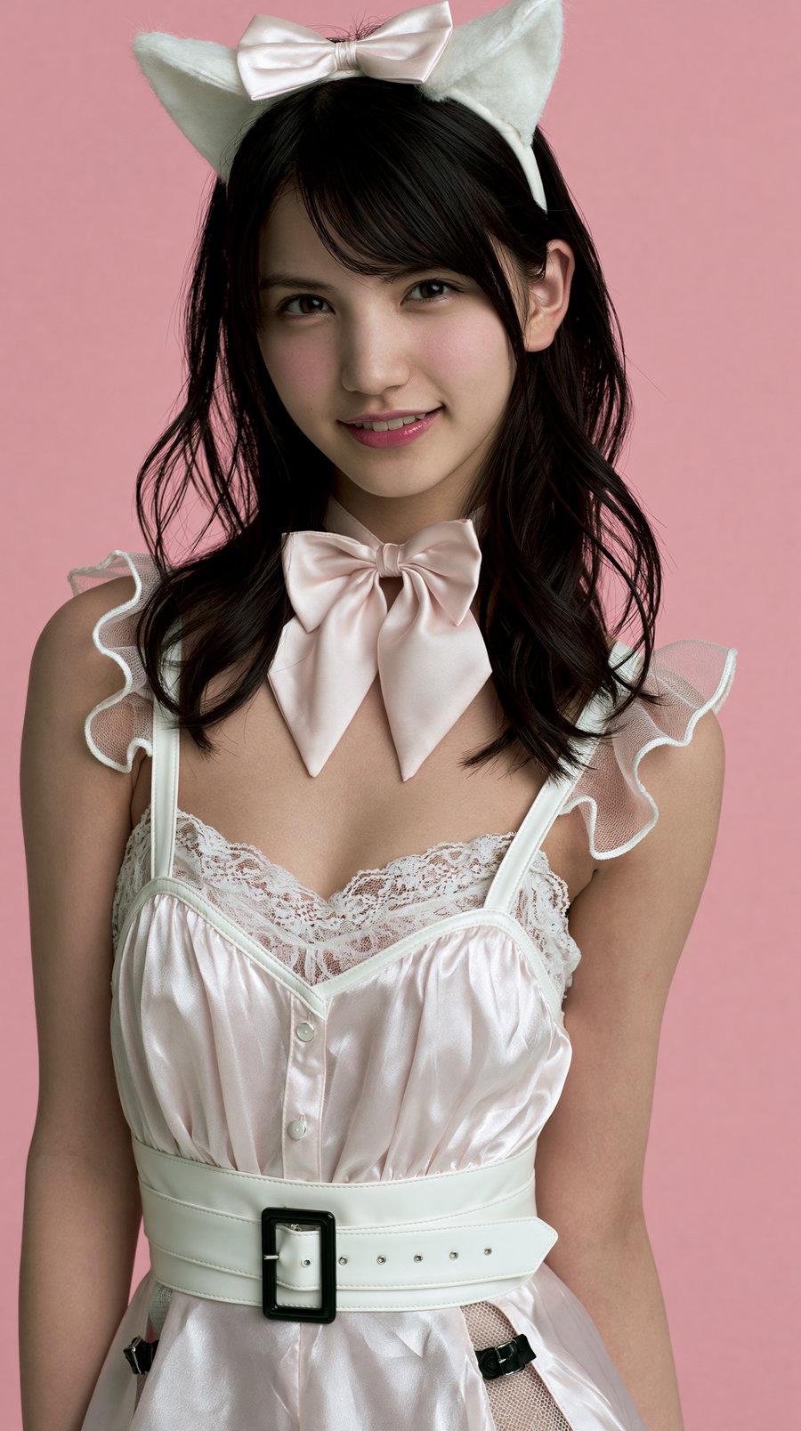 A girl in a pink idol costume with cat ears, smiling against a pink background